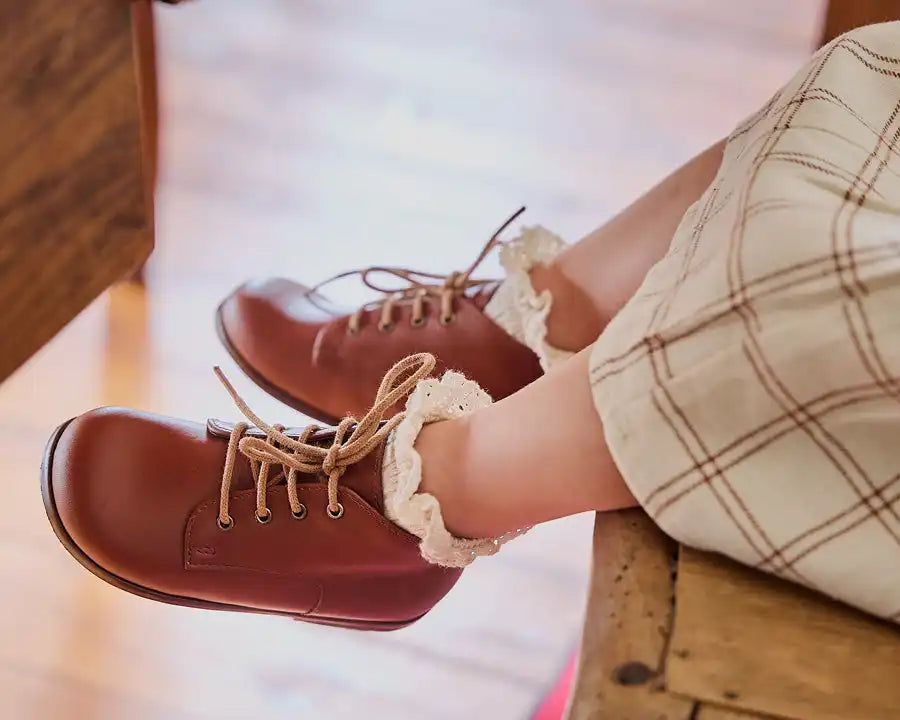 Bottes en cuir marron avec un bord en dentelle et des lacets couleur crème.