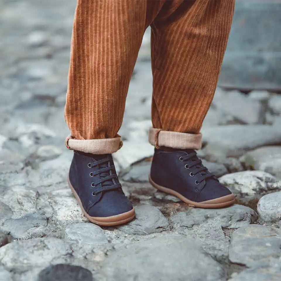 Pantalons en velours côtelé marron avec des poignets retroussés, associés à des bottines en cuir bleu marine.