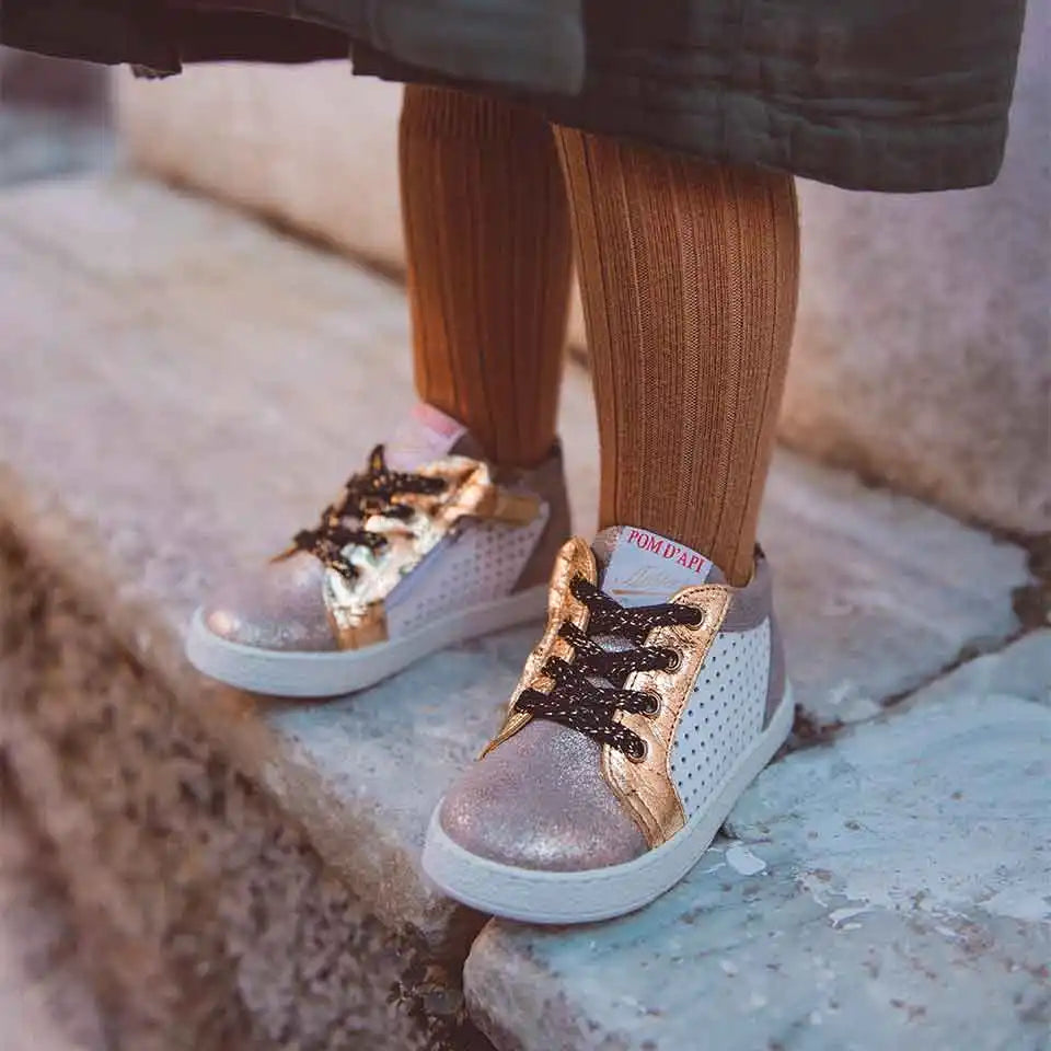 Baskets argentées brillantes avec des lacets marron et des chaussettes orange côtelées.